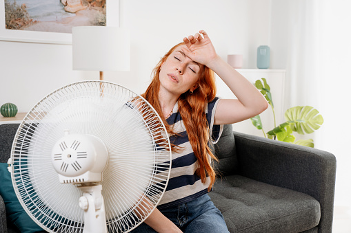 Young woman suffering summer heat wave at home