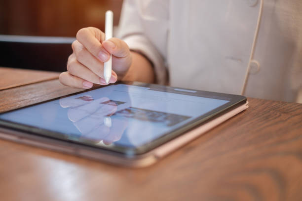 istock woman using tablet for sms messages, hand holding pencil typing touchscreen mobile phone in cafe or modern office. lifestyle, technology, Social media and network concept 1408012109