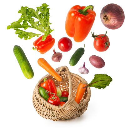 Fresh ripe vegetables fly into the basket from above. Vegetable harvest levitation on a white background. Isolated.