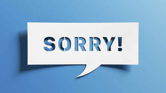 Sorry message to express regret, remorse, apology for error, mistake, guilt and request forgiveness. Concept with word written in cut out paper in shape of speech bubble with blue background.