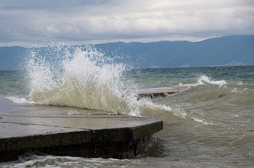 waves are crushing against a pier at lake ohrid in Macedonia on a stormy day