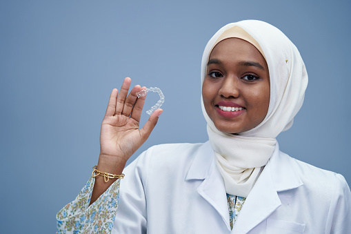 Hijab dentist holding clear dental brace
