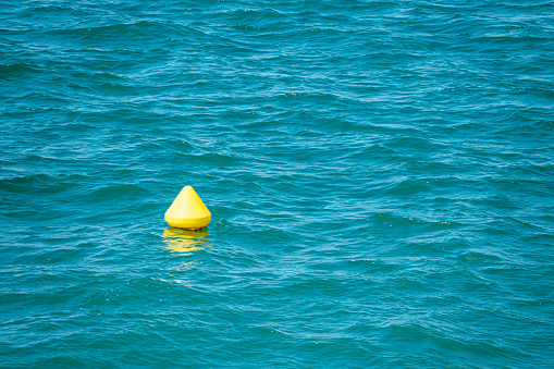 Yellow buoy on blue wavy sea surface