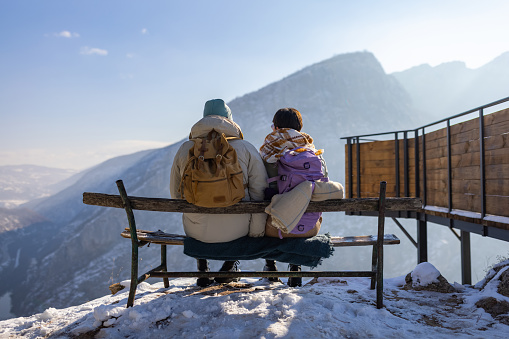 Young Caucasian couple hiking on the mountain during winter day and admiring the view
