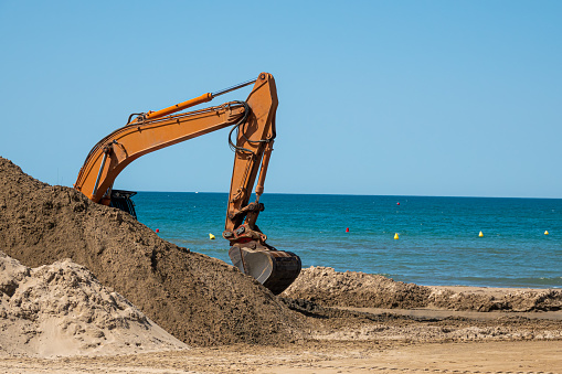 Construction work on the seashore. An excavator dug up a wet sand