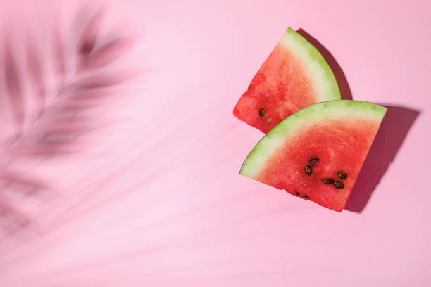 istock Delicious ripe watermelon and tropical leaf shadow on light pink background, flat lay. Space for text 1408021136