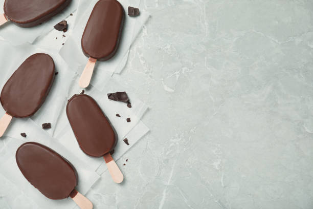 istock Glazed ice cream bars and chocolate chunks on light grey table, flat lay. Space for text 1408022187