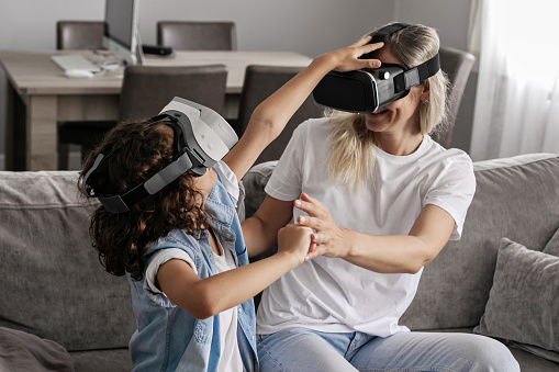 Mother and son wearing virtual reality headset vr glasses in living room at home having fun interacting with virtual reality playing games