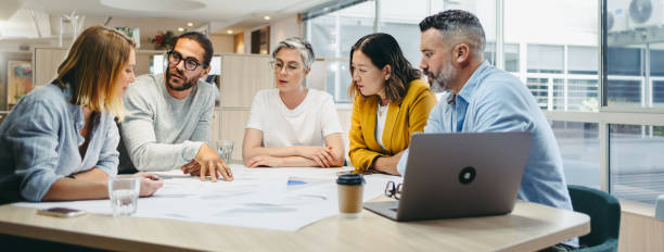 wielokulturowy projektant dzielący się pomysłami podczas spotkania - business meeting teamwork meeting mature adult zdjęcia i obrazy z banku zdjęć