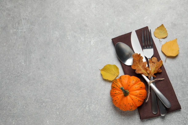 istock Cutlery, autumn leaves and pumpkin on light grey table, flat lay. Space for text 1408022434