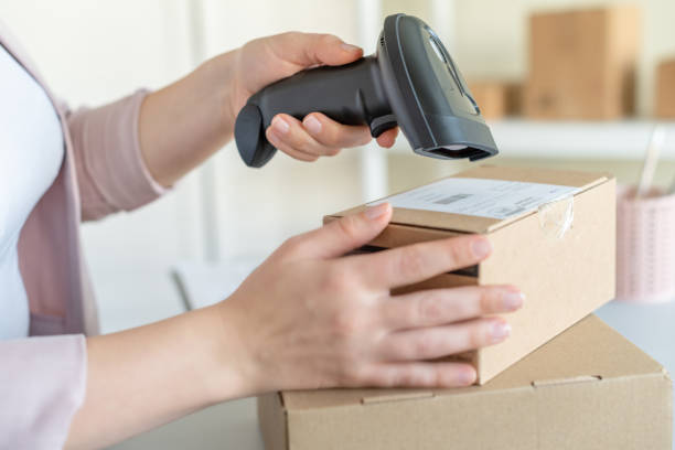 istock Female owner of start up small business using barcode scanner scanning retail drop shipping package postal parcel bar code. Warehouse worker. 1408022684