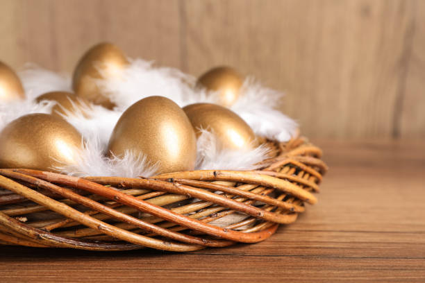 istock Golden eggs and feathers in nest on wooden table, closeup 1408022909