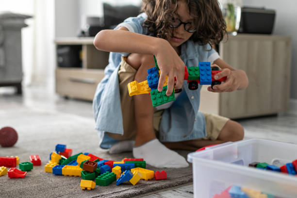 Little toddler boy playing with colorful plastic blocks at home building creative game, imagination