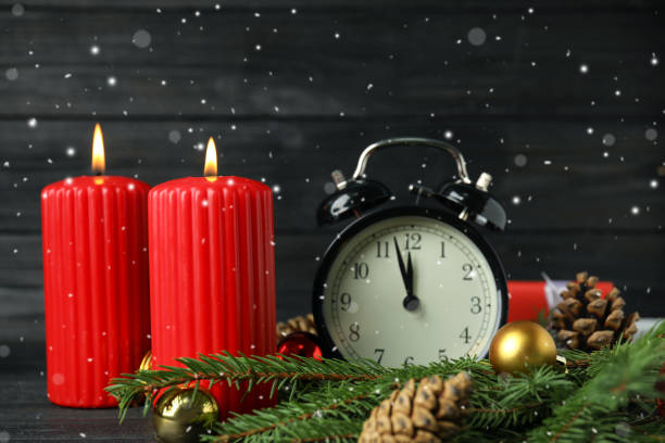 istock Snow falling on table with burning candles, alarm clock and festive decor. Christmas eve 1408022994