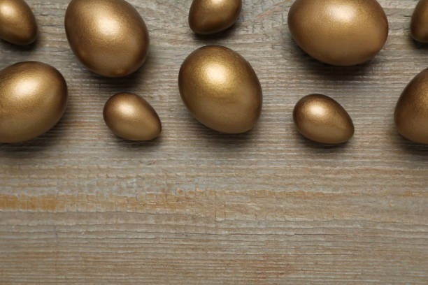 Golden eggs on wooden table, flat lay. Space for text Golden eggs on wooden table, flat lay. Space for text top gold ira stock pictures, royalty-free photos & images