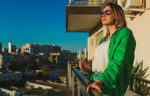 istock Woman with white wine enjoys the sunset on her balcony. 1408024385