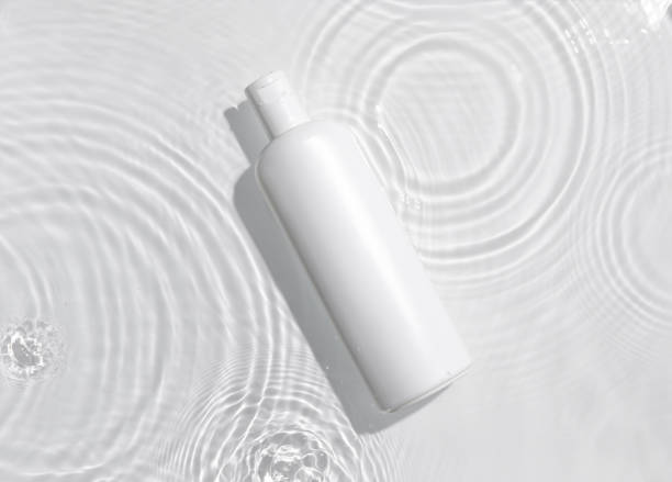 istock White cosmetic bottle on the water surface. Blank label for branding mock-up. Summer water pool fresh concept. Flat lay, top view. 1408024586