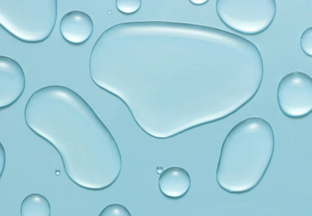 Liquid gel cosmetic drops texture on blue background. Skincare hygiene product closeup. stock photo