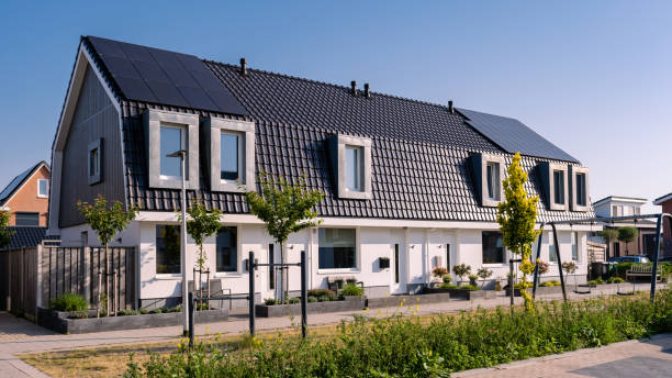 Newly build houses with solar panels attached on the roof against a sunny sky Newly build houses with solar panels attached on the roof against a sunny sky Close up of new building with black solar panels. Zonnepanelen, Zonne energie, Translation: Solar panel, , Sun Energy. solar panels on the roof of building in a city stock pictures, royalty-free photos & images