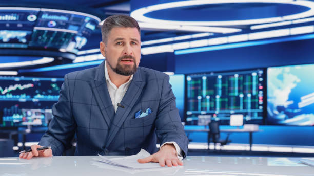 istock TV Live News Program: Charismatic White Male Presenter Reporting. Television Cable Channel Anchorman or Host Talking about Important Events. Network Broadcast Mock-up. Modern Newsroom Studio 1408025771
