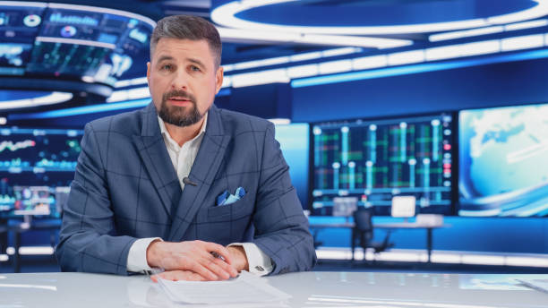 istock TV Live News Program: Charismatic White Male Presenter Reporting. Television Cable Channel Anchorman or Host Talking about Important Events. Network Broadcast Mock-up. Modern Newsroom Studio 1408025960