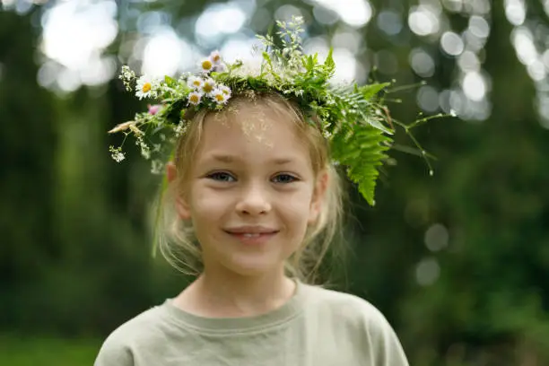 Portrait of a kind child girl in a herbal wreath. Unity with nature.