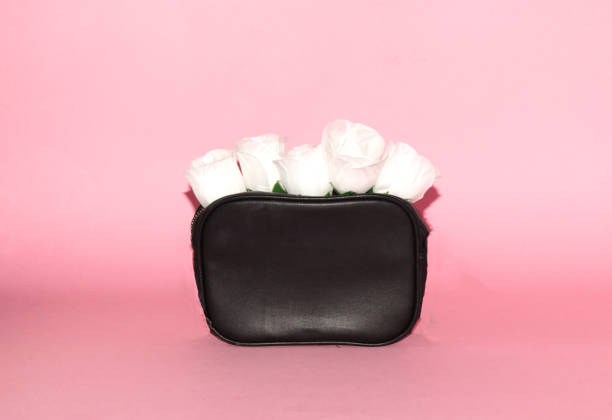 black purse with white flower head, creative art design, back to school, pink background