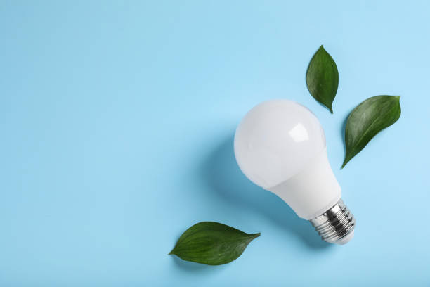 istock Light bulb and green leaves on color background, flat lay. Space for text 1408030623