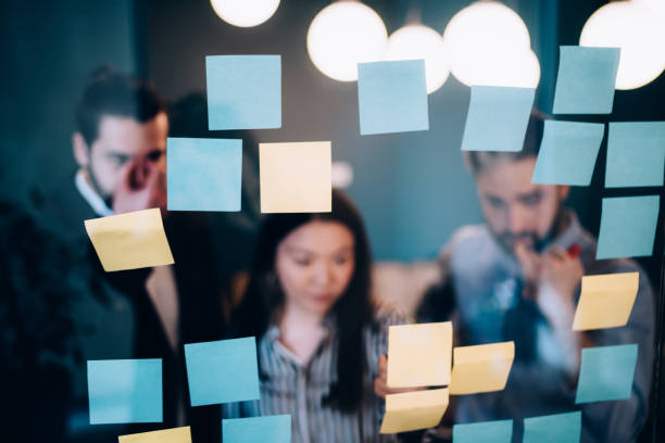 istock Concentrated team of managers standing and looking at sticky notes on wall 1408033711