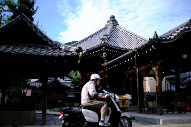 Newspaper delivery man rides scooter past Zen temple in Kyoto stock photo