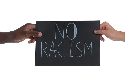 Men holding sign with phrase No Racism on white background, closeup