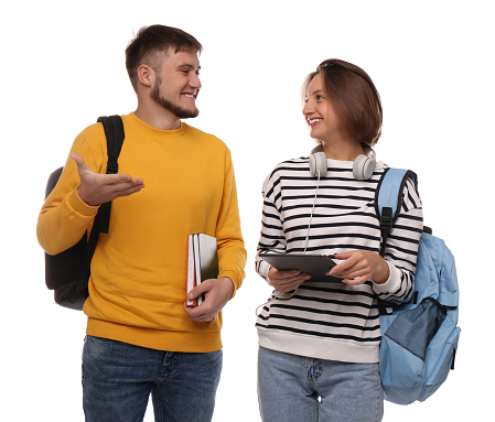 Young students with backpacks, books and tablet on white background