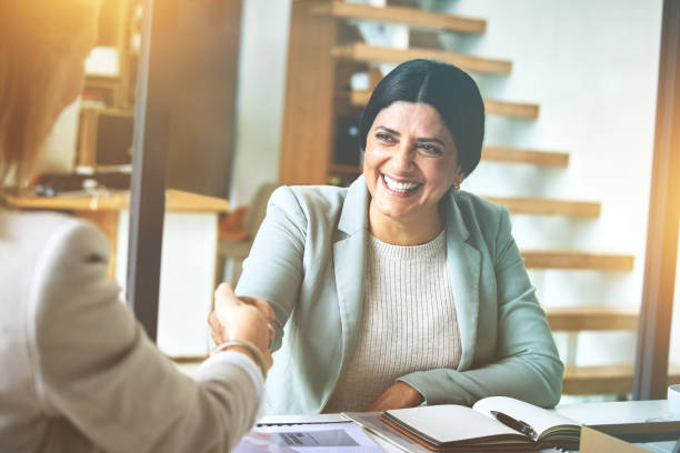istock Happy mature manager greeting, collaborating and networking during an interview to negotiate and agree on a deal or offer. Business woman giving handshake to a colleague during a meeting in an office 1408036335