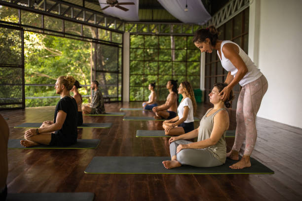 professeur de yoga animant un cours de yoga - yoga class caucasian young adult group of people photos et images de collection