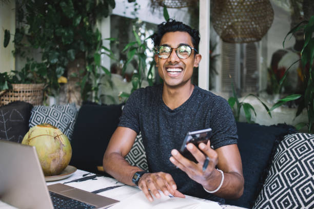 istock Overjoyed youthful ethnic male using smartphone at cafe 1408037712