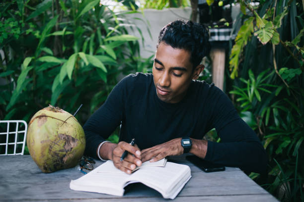 istock Attentive adult ethnic man reading book and taking notes in notepad in garden 1408037730