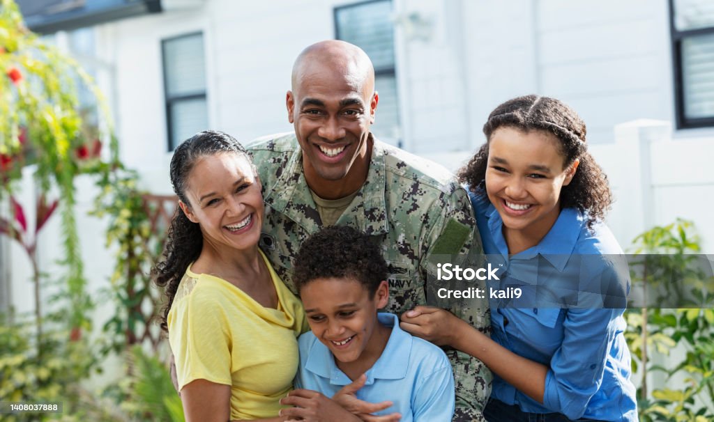 African-American navy veteran with multiracial family Portrait of a proud African-American navy veteran with his multiracial family, standing together outside their home. The two children and their mother are African-American and Caucasian. The parents are in their 40s, their daughter is 12 years old and their son is 8. All except the boy are smiling at the camera. Family Stock Photo
