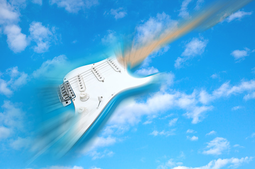 blue electric guitar flying in blue cloudy sky