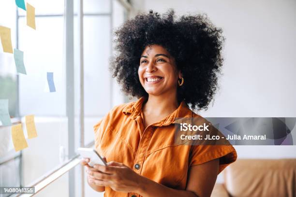 Happy Black Businesswoman Using A Smartphone In A Creative Office Stock Photo - Download Image Now