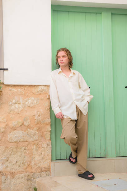istock Young man poses in white shirt and brown pants 1408041383