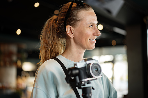 Woman photographer with professional camera indoors, closeup photo