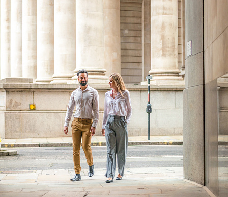 Two business colleagues walking together in the heart of London's financial district, the City of London.