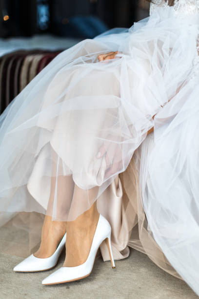 istock Bride putting on her white wedding shoes 1408043054