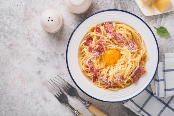 istock Carbonara pasta. Spaghetti with pancetta, egg, parmesan cheese and cream sauce on old gray concrete table background. Traditional italian cuisine and dish. Pasta alla carbonara. Top view. 1408044068