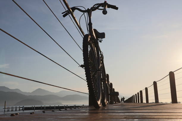 silhouette of a bicycle on a wooded bridge pier in the port during sunrise at ubatua, brazil - sao paulo south america marina southeastern region imagens e fotografias de stock