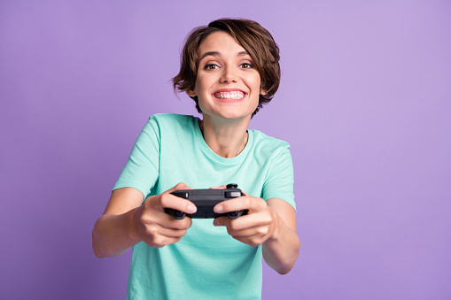 Photo of cute funny young lady wear casual teal outfit holding playing console isolated purple color background.