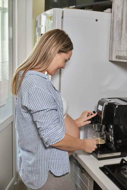 istock Woman having cup of coffee at the kitchen, using coffee machine 1408045939