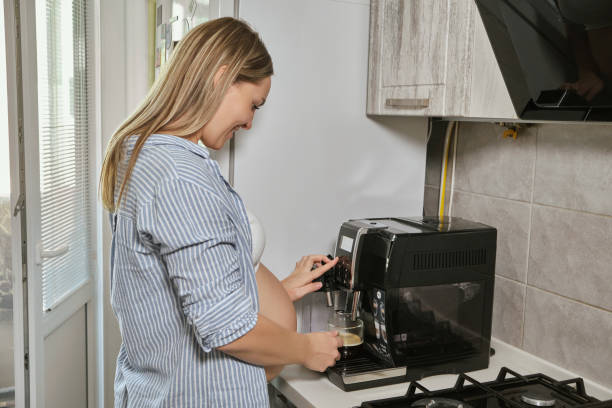 istock Woman having cup of coffee at the kitchen, using coffee machine 1408045944