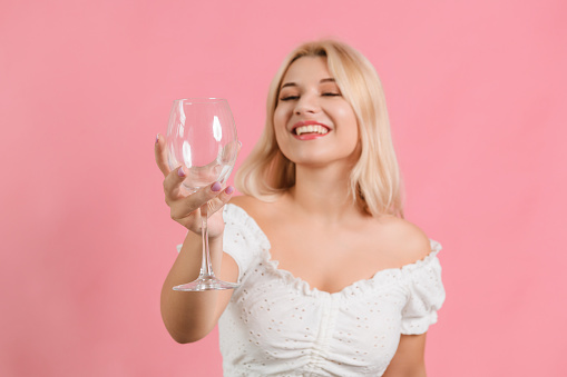 a girl in light clothes with a glass in her hand on a pink background