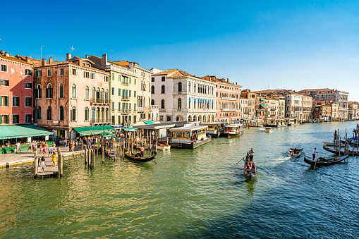 View of Grand Canal in Venice, Italy with vaporetto and gondolas navigating on water.